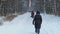 Ordinary people walk on snowy sidewalk in winter park