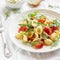 Orecchiette pasta with cherry tomatoes, arugula and Parmesan cheese on a white plate