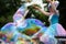 Orel, Russia, May 26, 2019: Twin Festival. Happy woman in bright fancy costume making huge rainbow soap bubble