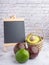 Organic avocado with seed, avocado halves in a basket, and whole fruits with a small blackboard on a gray stone background with a