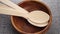 Organic biodegradable bamboo wooden spoon set falling into an empty rustic bowl in slow motion.