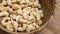 Organic cashew nuts in a rustic wood braid bowl close up.