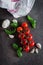 Organic Cherry Tomatoes with basil and garlic on dark browm concrete stone background. Top view