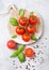 Organic Cherry Tomatoes on the Vine with basil and pepper on chopping board on stone kitchen background.