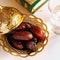 Organic dates arabic golden plate, cup of pure drinking water and quran book. Holy month Ramadan concept. Copy space