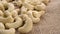 Organic dried cashew nuts on rustic rough burlap. Macro.