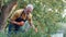 Organic farming. Happy mature man gardener wearing apron and protective gloves watering flowers or plant and smiling