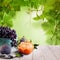 Organic food background with green grape leaves, tangerine fruits, figs and grape on white wooden board