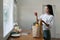 Organic Food Delivery. Happy young woman unpacking bag with Fresh Vegetables in kitchen