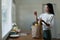 Organic Food Delivery. Happy young woman unpacking bag with Fresh Vegetables in kitchen