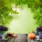 Organic fruits, green leaves and wooden table board against greenery foliage background