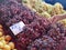 Organic grapes on showcase at the farmer`s market. Female buyer hand.