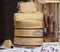 Organic hard cheese wheels stacked and salami hanging, on a shelf of an outdoor rural market in northern Italy