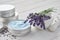 Organic lavender cream, mortar and bunch of dry lavender flowers on white wooden table