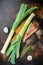 Organic leek stalks with herbs ingredients for cooking Braised Leeks, onrustic metall background dark, top view with  space for