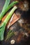 Organic leek stalks with herbs ingredients for cooking Braised Leeks, onrustic metall background dark, top view with  space for