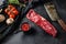 Organic machete or hanger butcher steak, near butcher knife with pink pepper and rosemary. Black background. Top view. side view