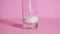 Organic milk is poured into a transparent glass on a pink background close up. 4k resolution slow motion. Video instruction for ho