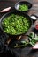 Organic mushy peas vegan recipe in frying pan and peas in bowl with mint shallot pepper and salt  over old pub wood surface close