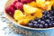 Organic oatmeal porridge in white ceramic bowl with raspberries, peaches and blueberries. Healthy breakfast - health and diet conc