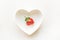 Organic one ugly strawberry in plate shaped as heart isolated on white background