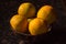 Organic oranges freshly plucked from farm is arranged on a wooden bowl isolated on a black background.
