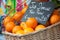 organic oranges in a wooden basket at the market with text in french on chalkboard