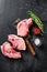 Organic  Pork meat chop over american classic butcher knife or cleaver with spices and rosemary and red pepper on black slate