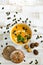 Organic pumpkin soup in a white bowl framed by chestnuts and chestnut bread and pumpkin seeds