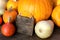 Organic Pumpkins and a board with copyspace on wooden background