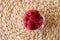 Organic raspberries in the glass on the natural straw table mat. Straw background. Healthy snack.