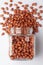 Organic red-brown peanuts Arachis hypogaea,  spilled and in a glass jar,