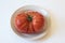 Organic red heritage tomato on a shallow dish, centered, isolate