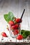 Organic red strawberries glass and mint leaves on rustic wooden background