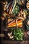 Organic root vegetables in harvest basket on dark rustic kitchen table background with ingredients for tasty cooking with greens