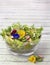 Organic salad decorated with edible pansy flowers on wooden back