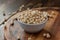 Organic soybeans at white ceramic bowl over wooden table.