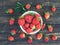 Organic strawberries in metal bowl on rustic wooden background. Summer gifts and harvest concept. Top view