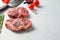 Organic top blade steak, raw beef meat with seasonings, rosemary and butcher cleaver. White textured background. Side view with