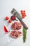 Organic top blade steak, raw beef meat with seasonings, rosemary, garnet, rose wine glass and butcher cleaver. White textured