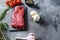 Organic Tri-tip, triangle roast marbled beef on black plate , marbled beef with herbs tomatoes peppercorns over grey stone surface