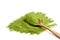 Organic wheatgrass or barley grass powder in wooden spoon isolated on white. Detox superfood