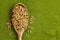 Organic wheatgrass seeds for sprouting in spoon on weatgrass powder background. Top view, copy space