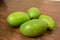 Organic Young Green Mangoes Branch Macro isolated on Wooden Table sour fruits.