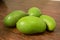 Organic Young Green Mangoes Branch Macro isolated on Wooden Table sour fruits.