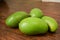 Organic Young Green Mangoes Branch Macro isolated on Wooden Table sour fruits.