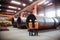 In an organized pipe manufacturing facility, three heavy industry engineers stand near a robotic welding machine