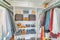 Organized unisex small walk in closet interior with shoe rack in the middle