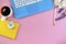 Organizer, pen, yellow diary, clock, coffee and blue notebook on pink background