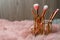 Organizer with set of professional makeup brushes on furry fabric against wooden background